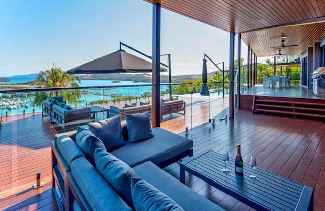 A Large Deck With a Couch , Table , and Umbrellas Overlooking the Ocean — Coral Coast Building & Management in Cannon Valley, QLD