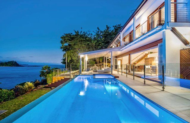 A Large House With a Large Swimming Pool in Front of It — Coral Coast Building & Management in Cannon Valley, QLD