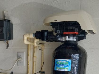 A water filter is attached to a wall with a phone number on it