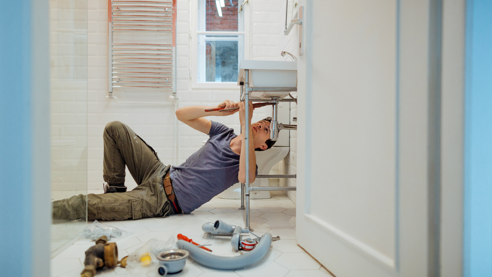 a man is laying on the floor fixing a sink