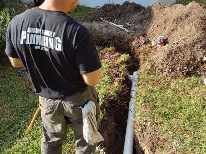 A man wearing a black shirt that says plumbing