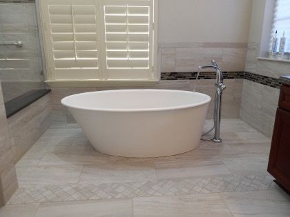 A bathroom with a bathtub and a window with shutters.