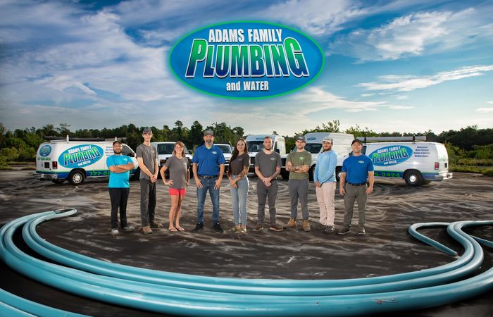 a group of plumbers are posing for a picture in front of their vans