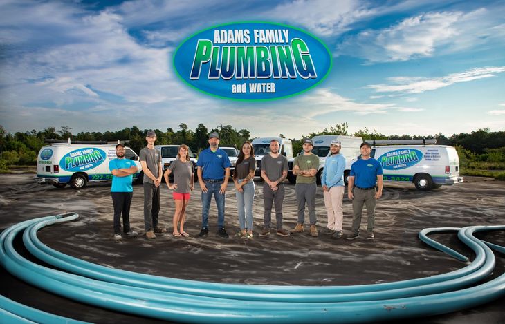 a group of people standing in front of a row of plumbing vans