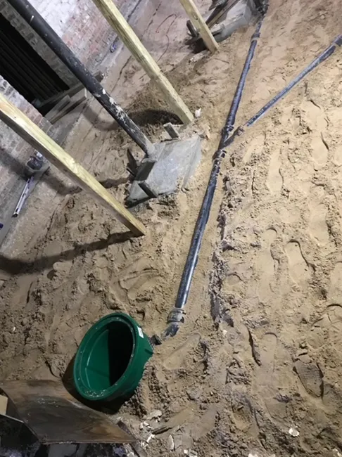 A green bucket is sitting in the dirt next to a shovel.