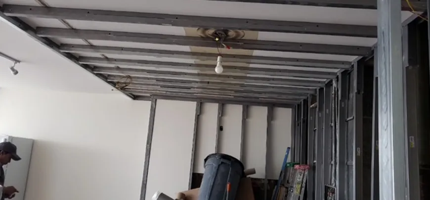A man is working on the ceiling of a room.