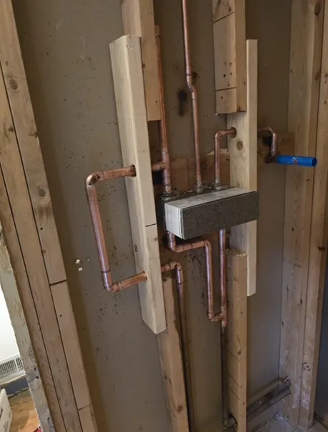 A wooden wall with copper pipes attached to it.