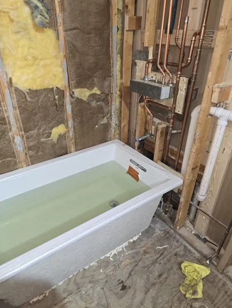A bathtub is filled with water in a bathroom under construction.