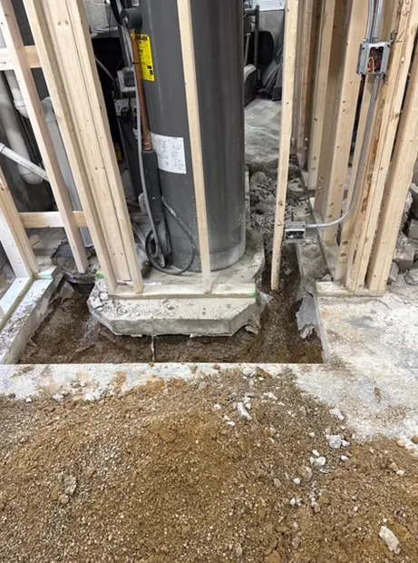 A water heater is being installed in a basement under construction.