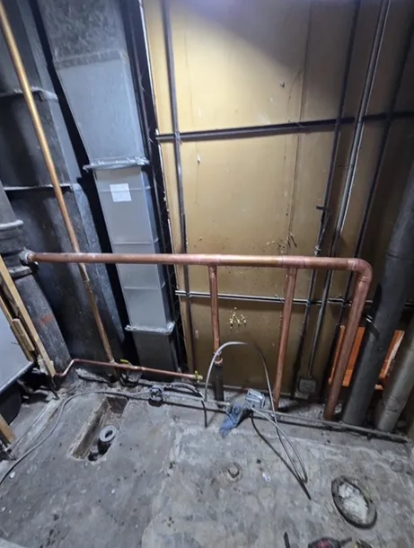 A room with a copper railing and pipes coming out of the ceiling.