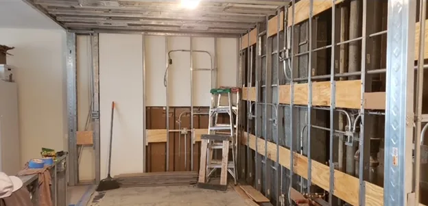 A room with a ladder and a broom in it is being remodeled.