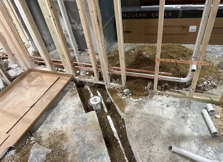 A building under construction with a lot of pipes coming out of the ground.