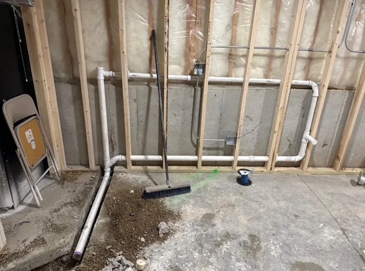 A broom is sitting on the floor in a basement under construction.