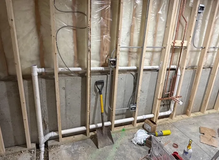 A shovel is leaning against a wall in a room under construction.