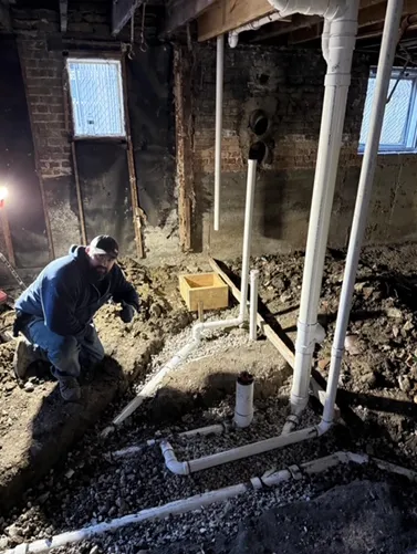 A man is kneeling in the dirt in a basement.