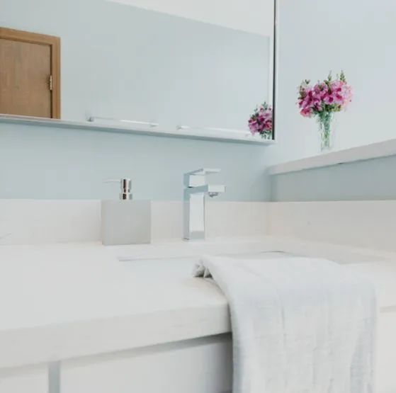 A bathroom with a sink a mirror and a vase of flowers