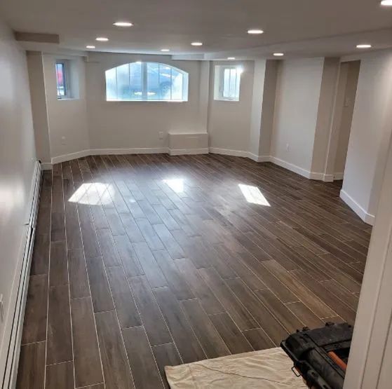 A large empty room with wooden floors and white walls.