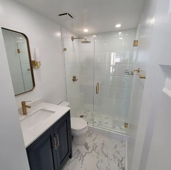 A bathroom with a sink , toilet , shower and mirror.