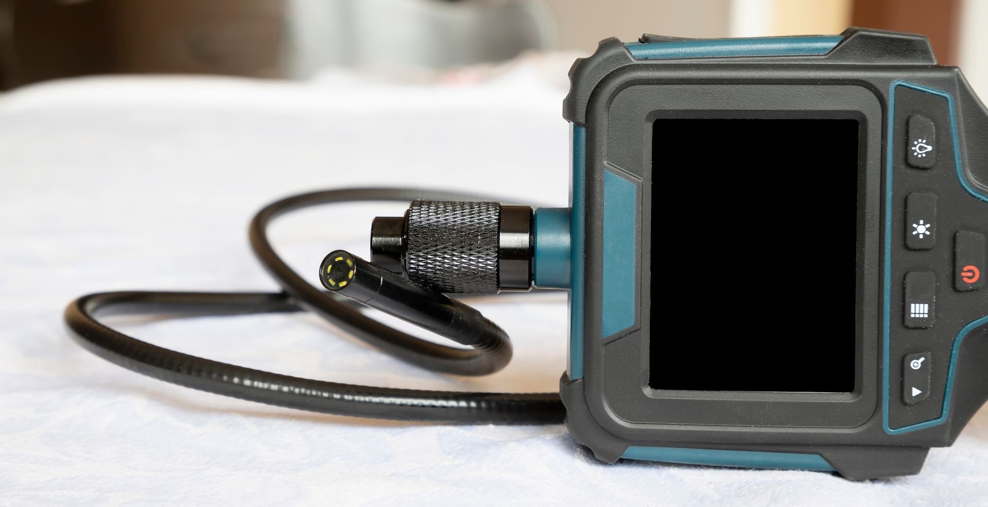 Compact black-and-blue electronic device with a coiled cable on a white surface