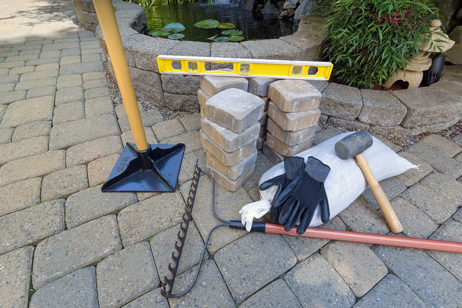 A brick patio with a level , gloves , a hammer , and a chain.