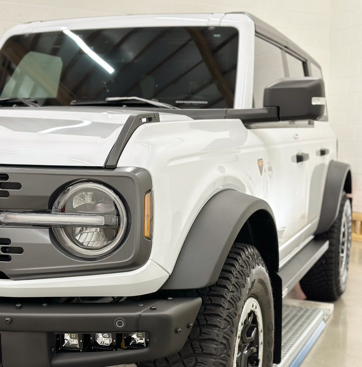 a white ford bronco is parked in a garage