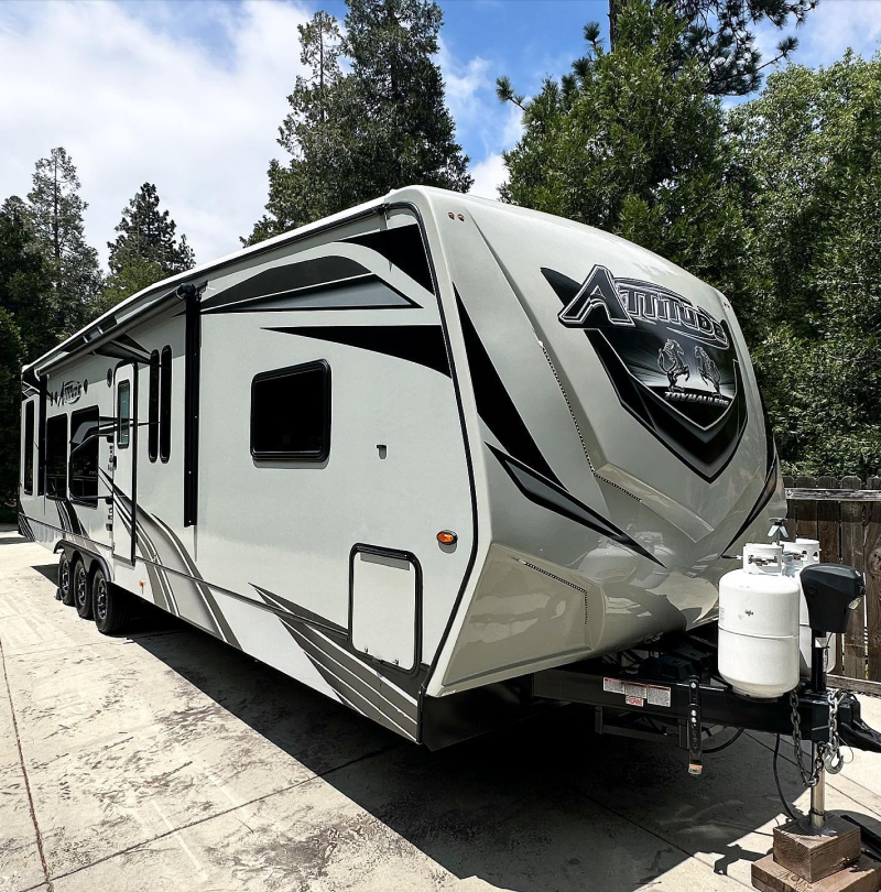 A white and black trailer is parked in a driveway.