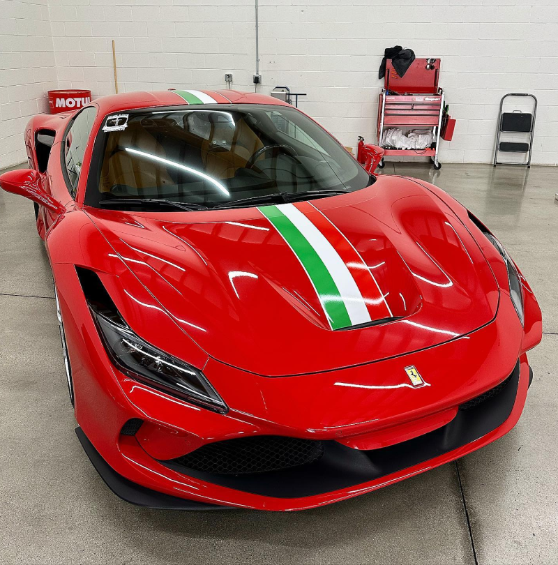 A red sports car is parked in a garage next to a motul sign