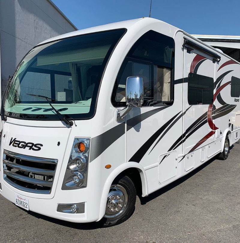 A white vegas rv is parked in front of a building