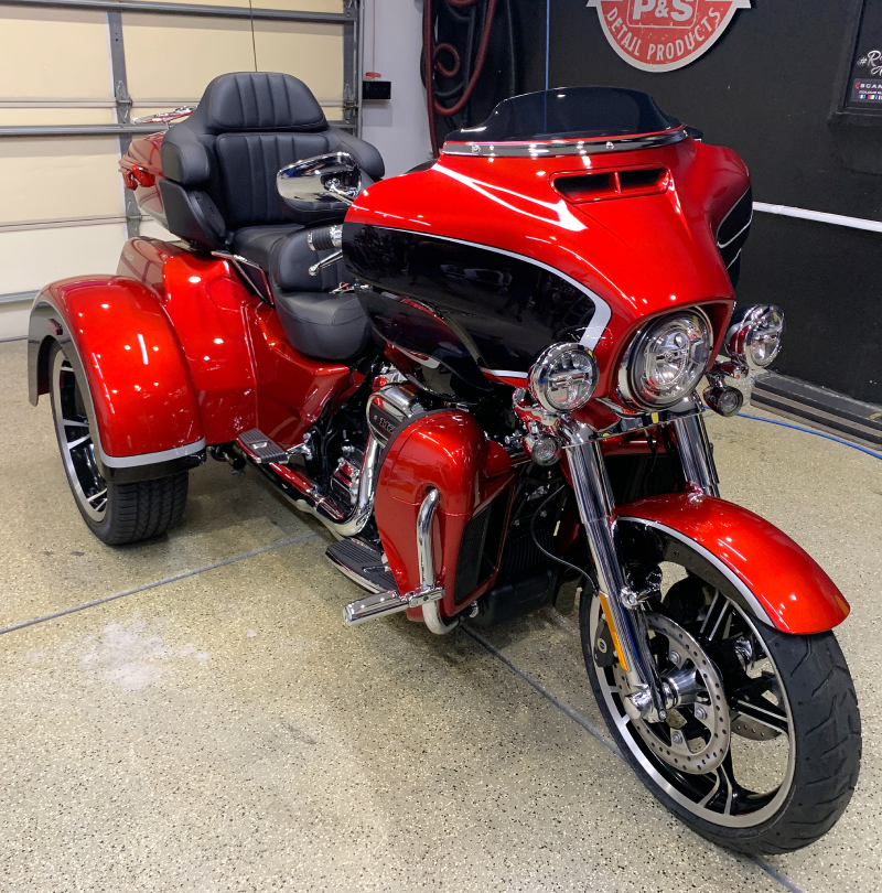 A red motorcycle with three wheels is parked in a garage