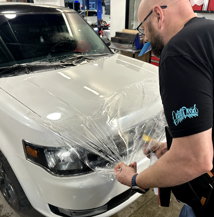 a man is wrapping a white car with clear plastic