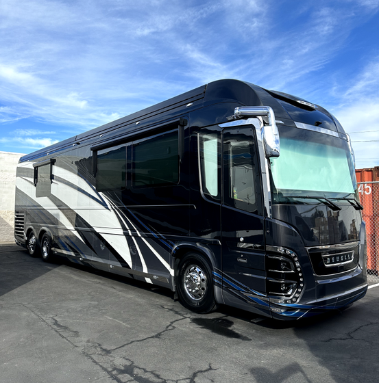 a large black and white rv is parked in a parking lot