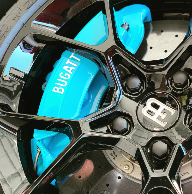 A close up of a bugatti wheel with blue brake calipers