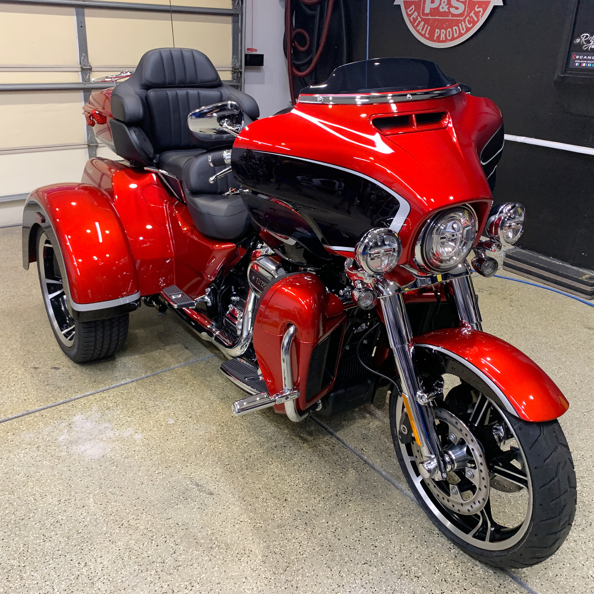 a red motorcycle with three wheels is parked in a garage
