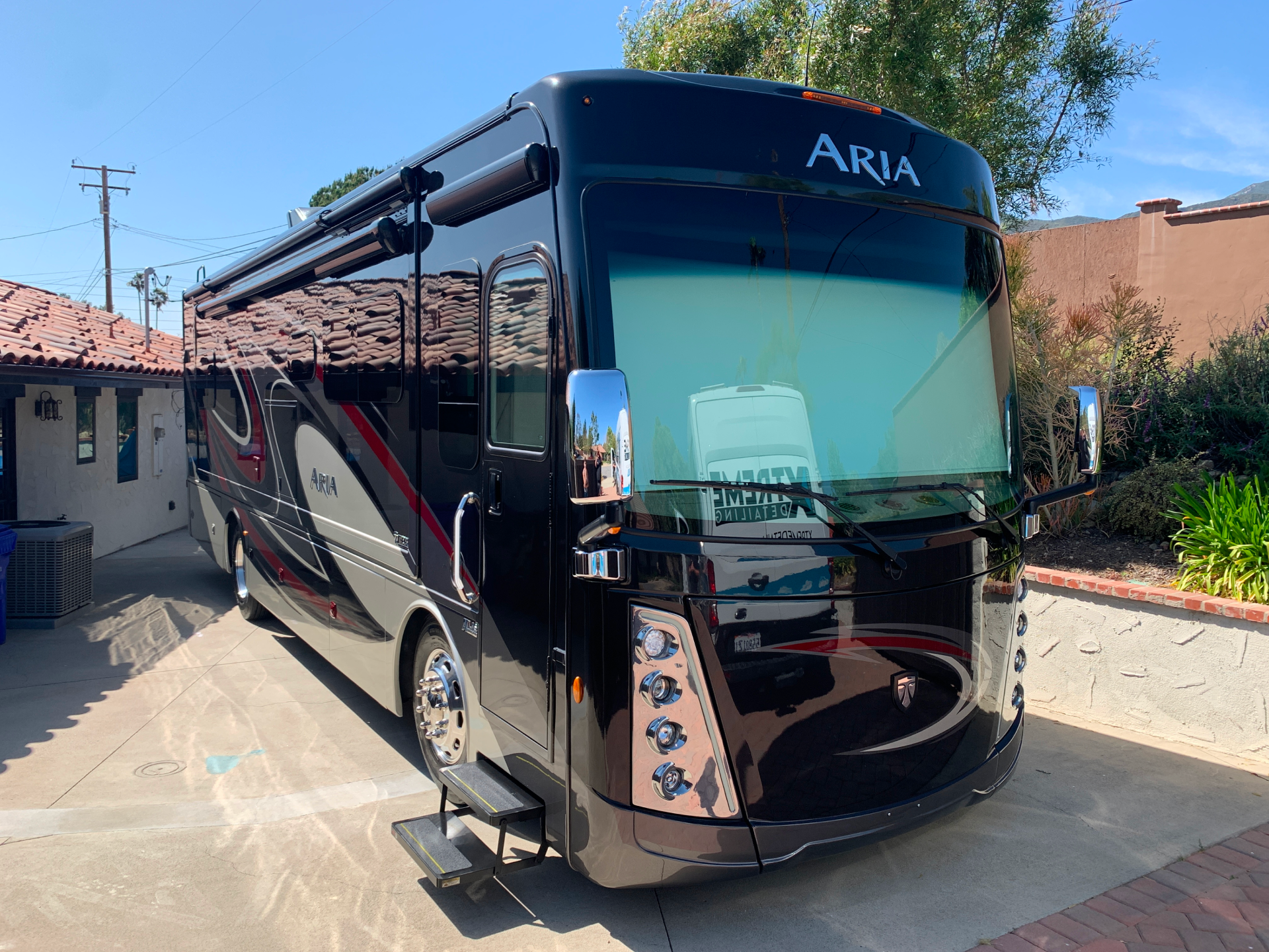 a large black aria rv is parked in a driveway .