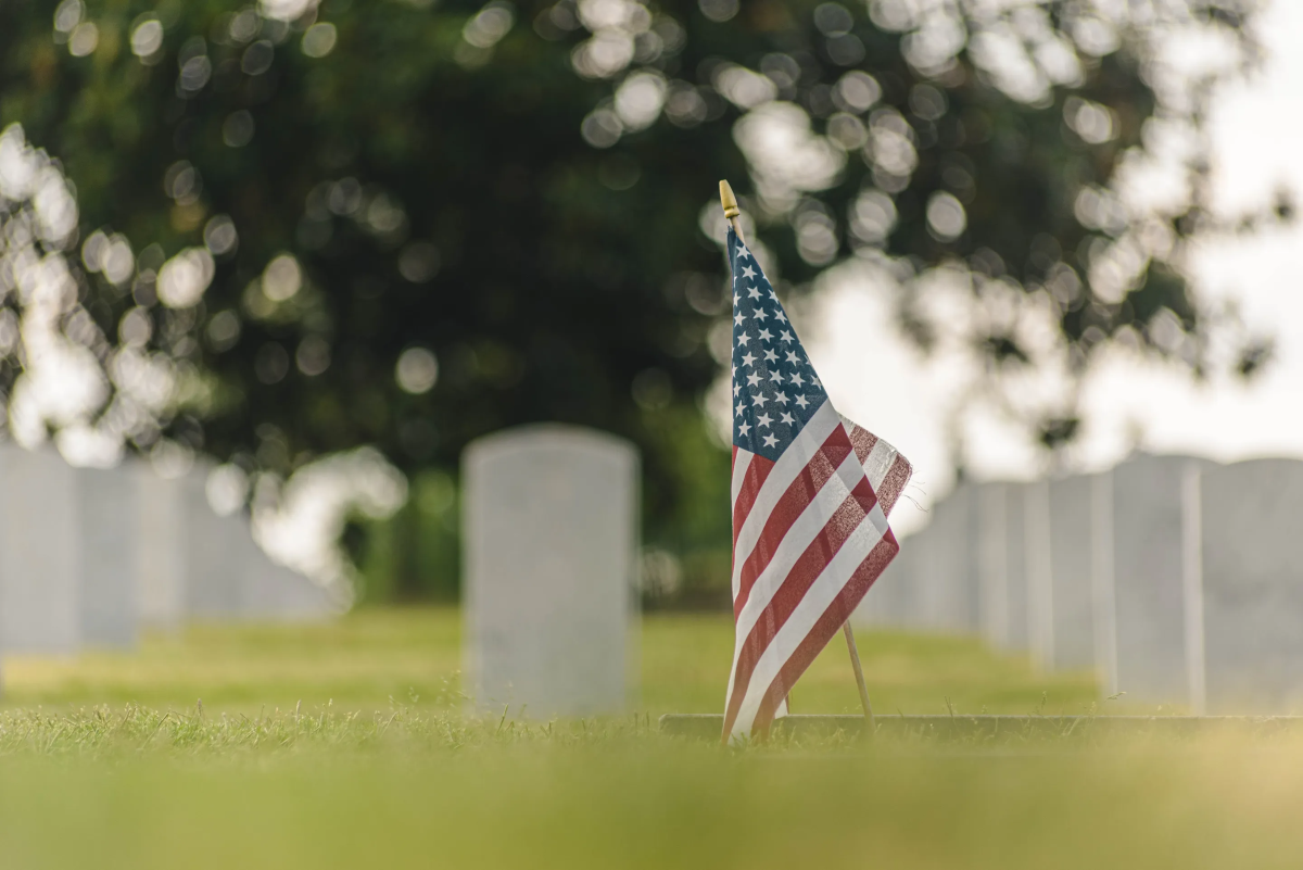 American flag on a grave in a cemetery, honoring fallen soldiers.