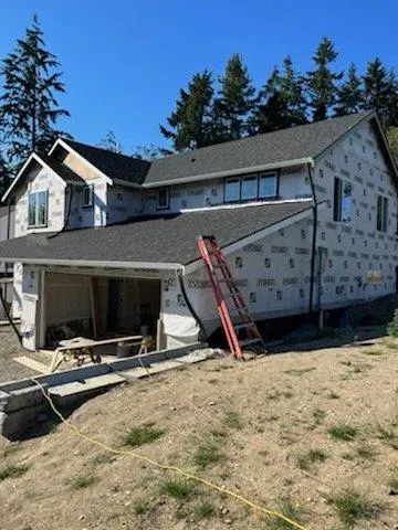 A house is being built on a hill with a ladder in front of it.