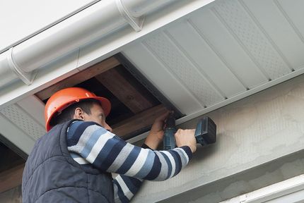 man drilling the exterior house ceiling