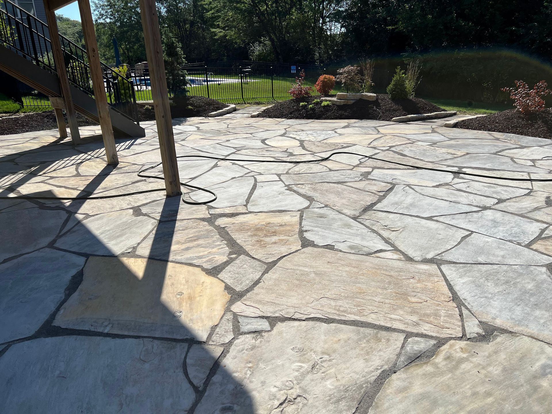 Flagstone patio with gray and tan stones in a sunny outdoor setting.