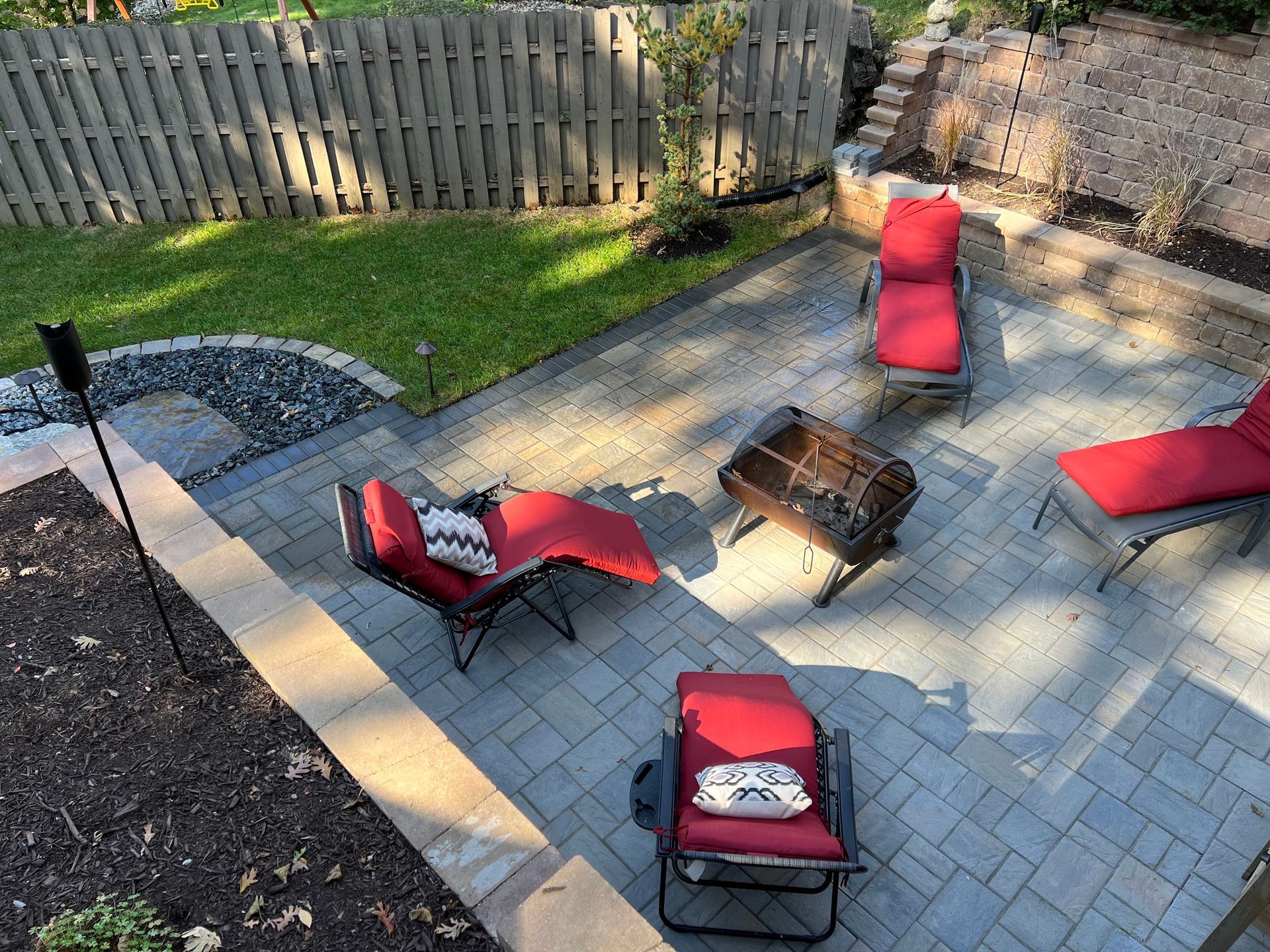 Patio with red lounge chairs, a fire pit, and a fenced yard.