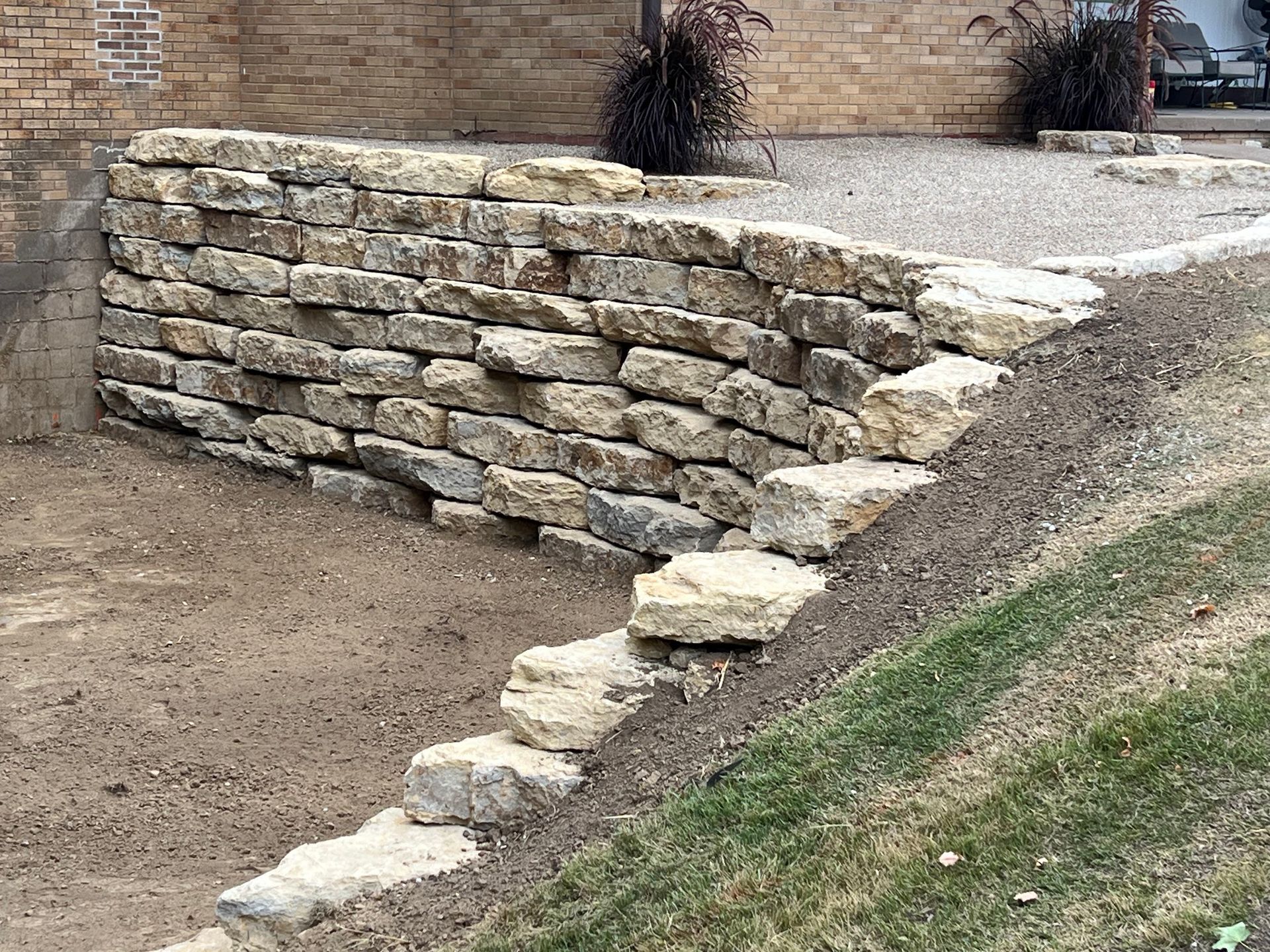 Stone retaining wall with steps built into a grassy slope.