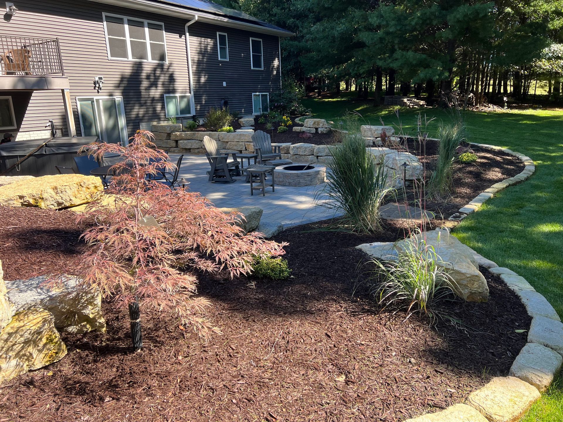 Backyard patio with stone retaining walls, fire pit, and landscaping.