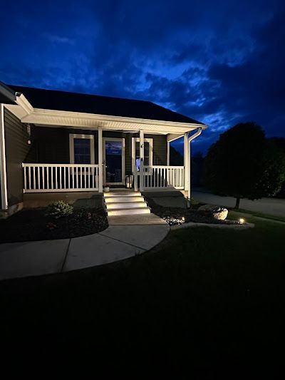 Night view of a house with illuminated porch and walkway, dark sky.