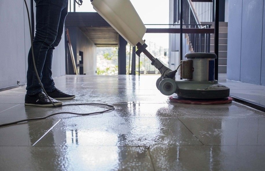 A Person is Cleaning a Tiled Floor With a Machine — South Pacific Cleaning in Bentley Park, QLD
