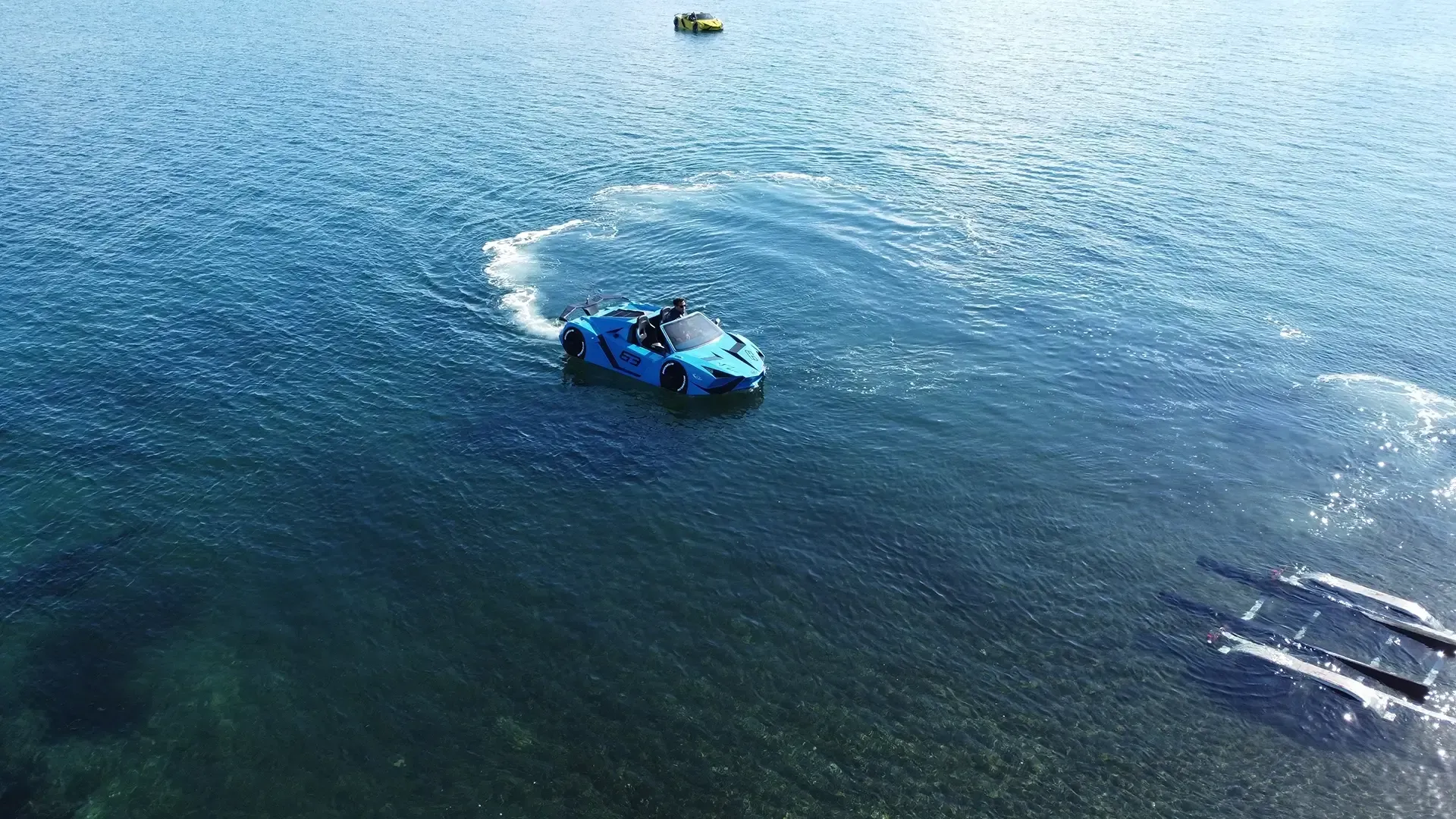 An aerial view of a blue car floating on top of a body of water.