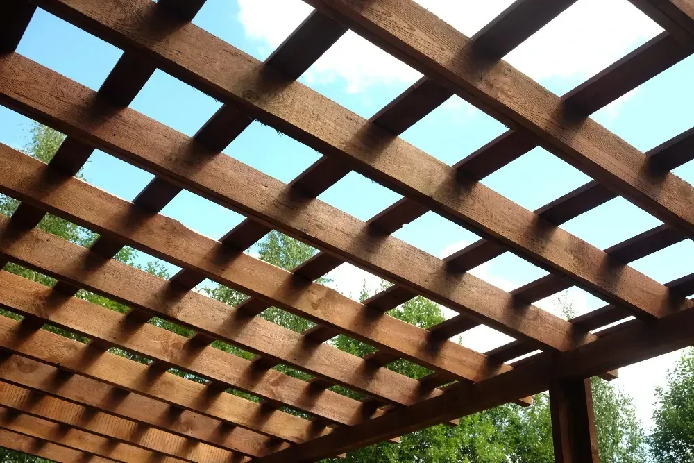 Looking up at the ceiling of a wooden pergola with trees in Lindenhurst, IL.