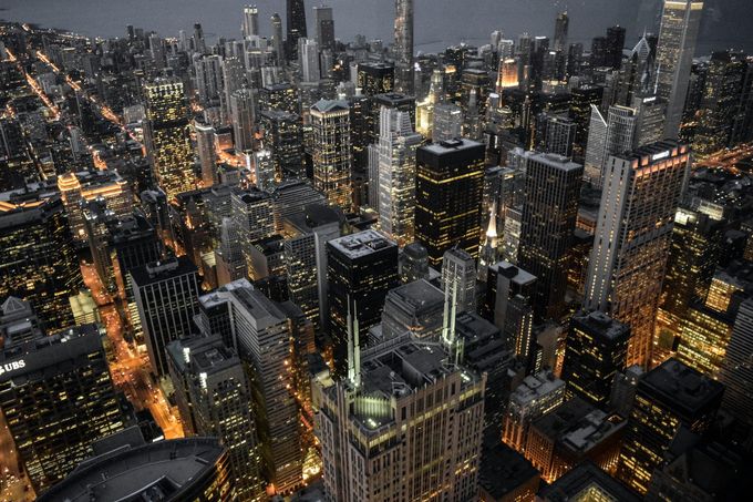 City skyline at night, tall buildings with illuminated windows.