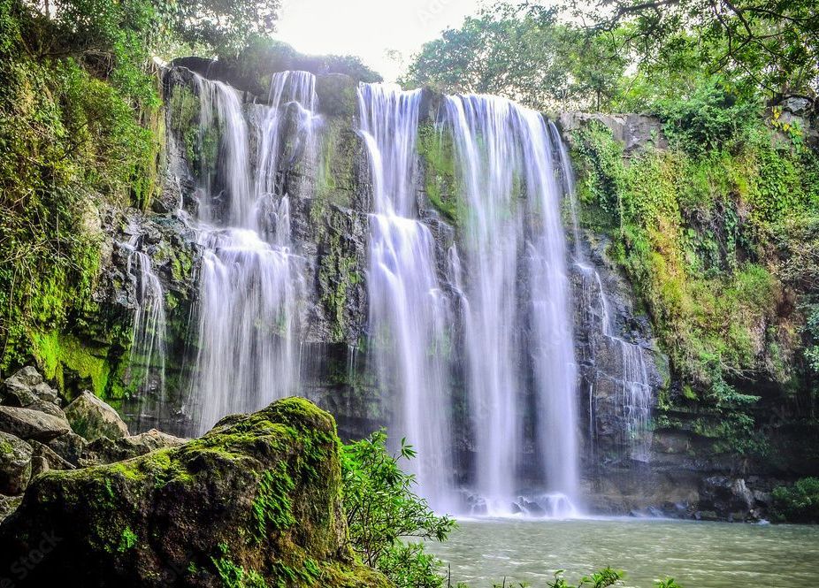 A waterfall is surrounded by trees and rocks in the middle of a forest.