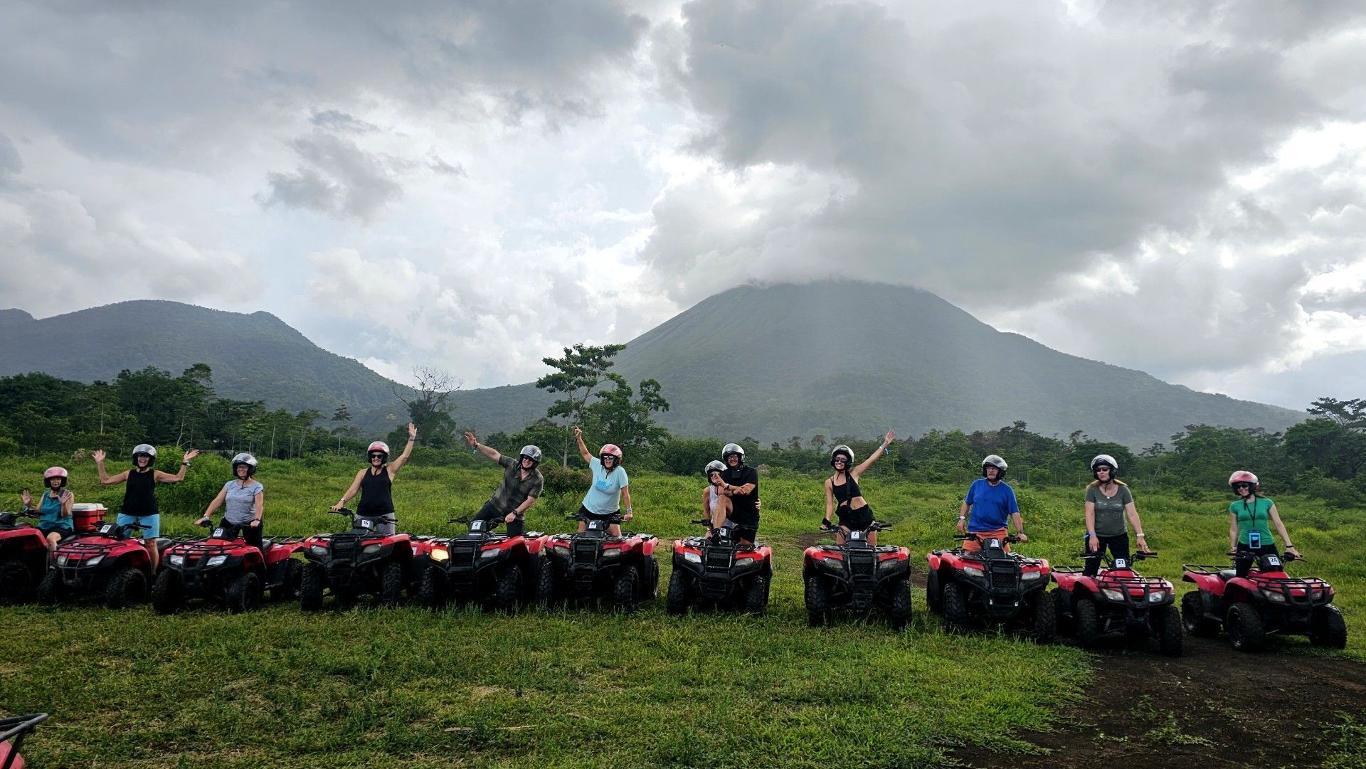 A group of people are standing next to each other on atvs in a field