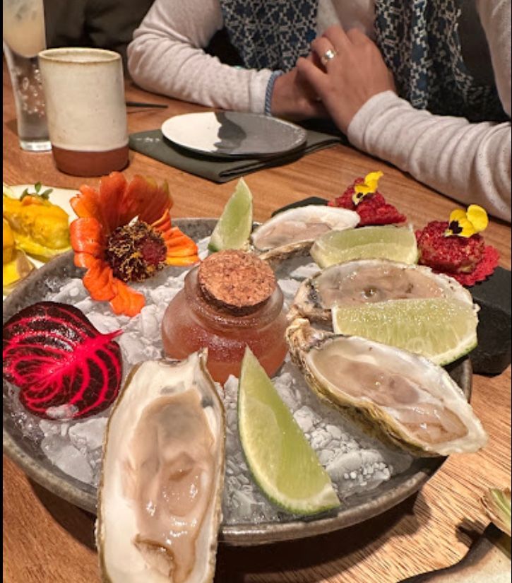 A plate of food with oysters and limes on ice