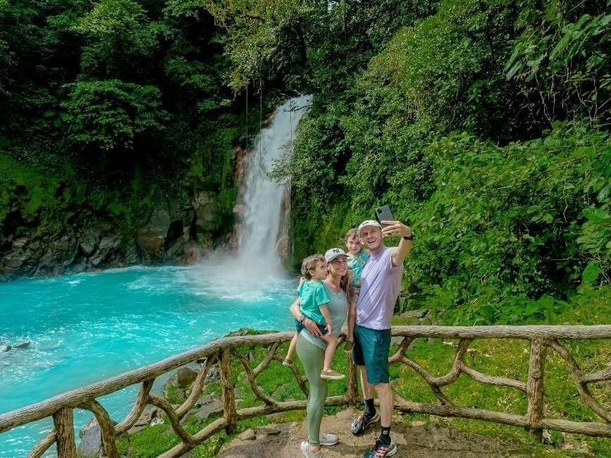 A family is taking a selfie in front of a waterfall